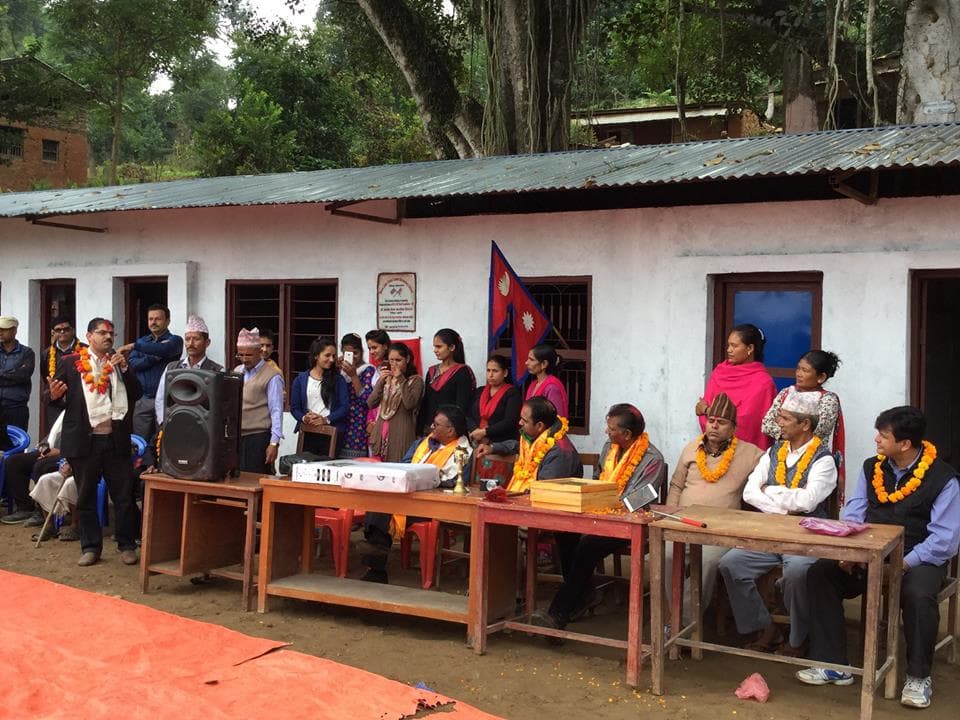 Community members and guests with garlands at a school handover ceremony in a Nepali village