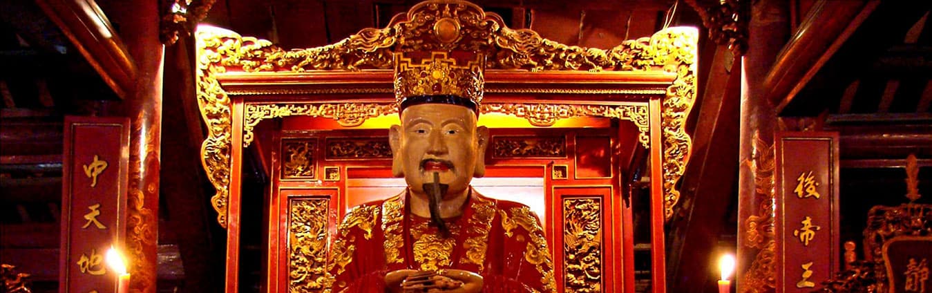 Gilded seated statue on an ornate red and gold altar in a Vietnamese temple