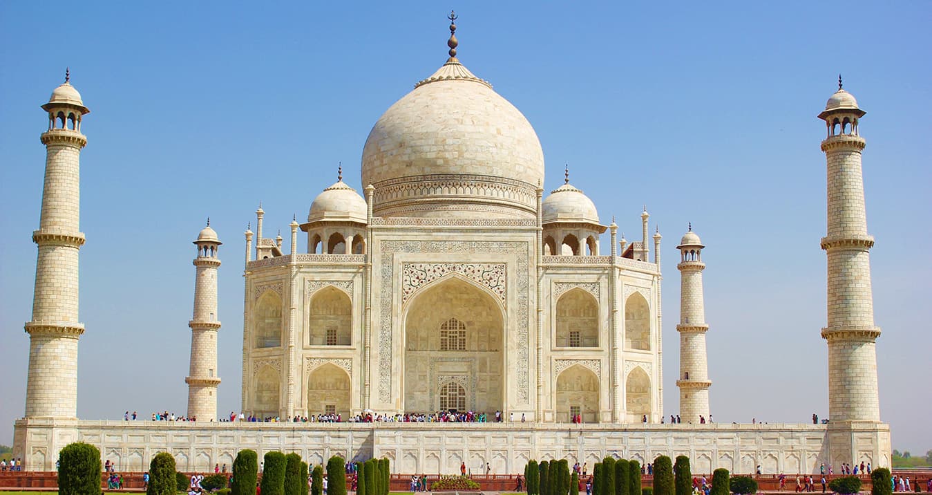 Taj Mahal white marble mausoleum with its four minarets under a clear blue sky