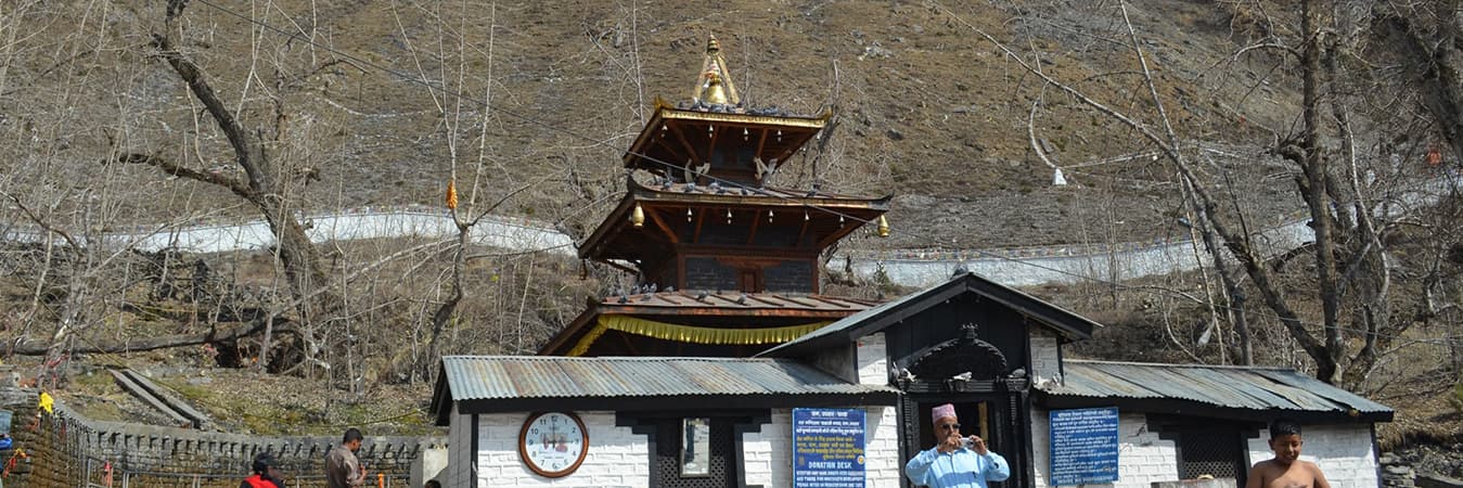 Pagoda-roofed temple above an entrance gate with pilgrims at Muktinath