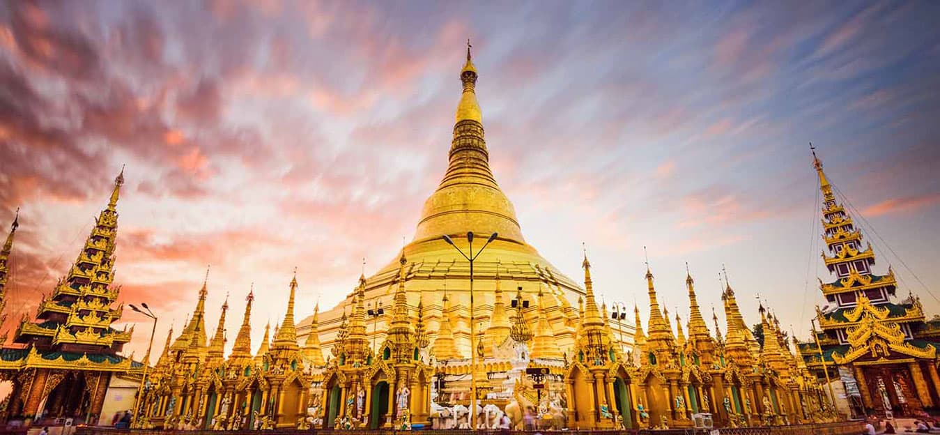 Gilded central stupa of the Shwedagon Pagoda ringed by golden spires at sunset