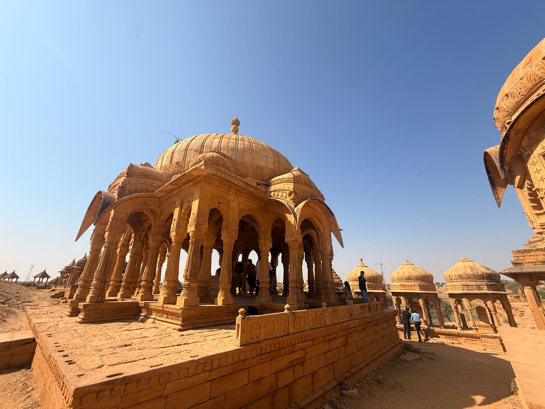Domed sandstone cenotaphs with carved pillars at Bada Bagh in Jaisalmer under a clear sky