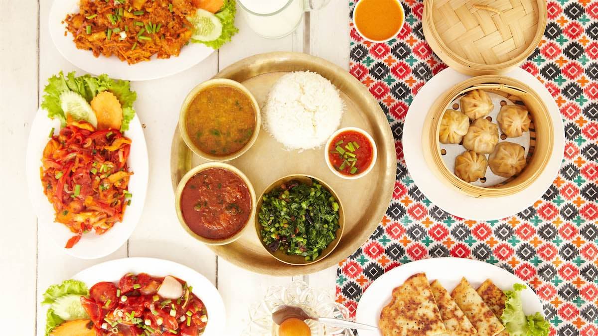 Nepali dishes on the table: dal bhat with curries, momos and vegetable sides