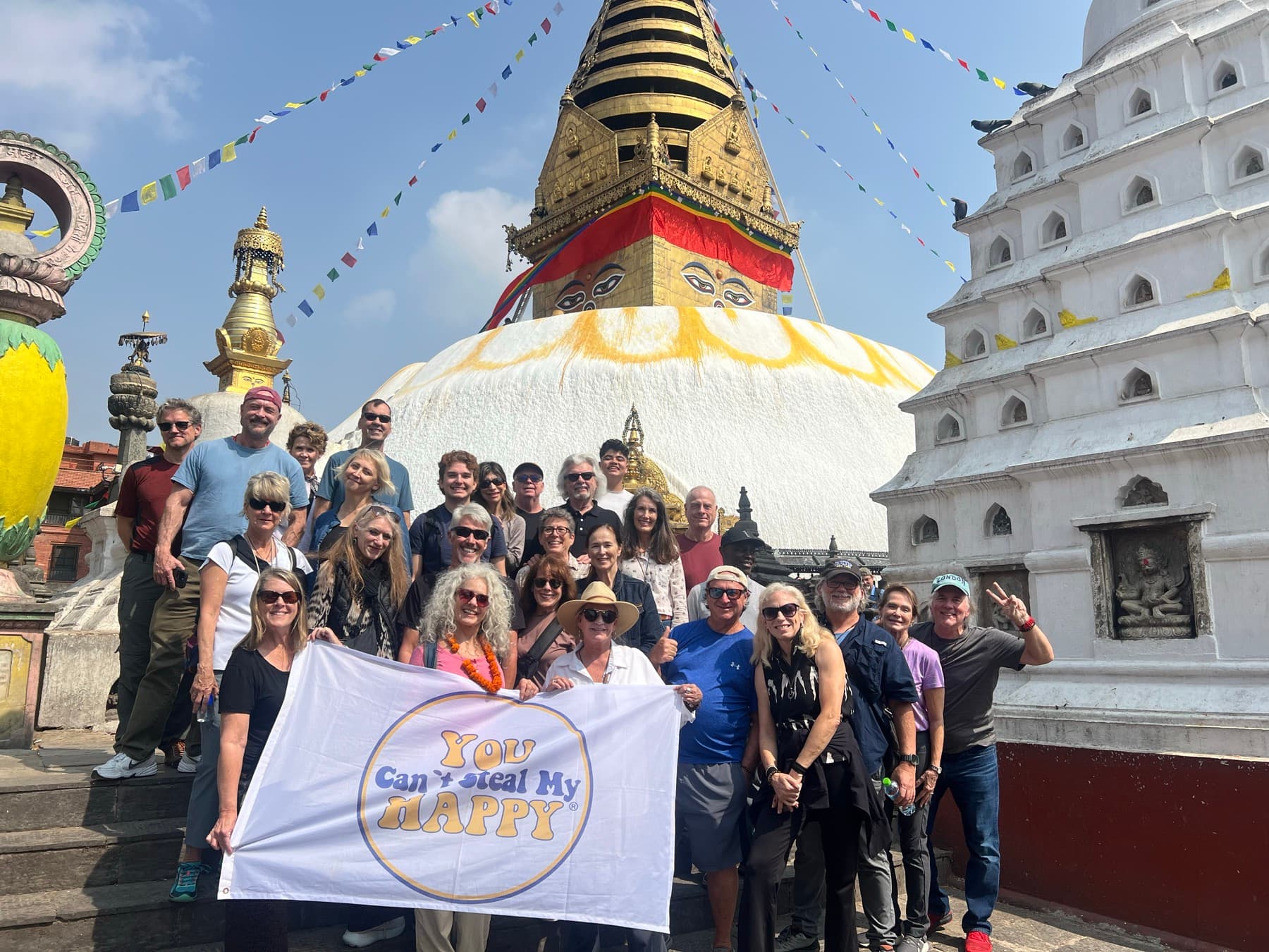 Large tour group holding a banner in front of the white stupa at Swayambhunath